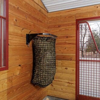 Hanging haynet in a wooden stall with protective red mesh and window, featuring EZ-fill slow feed design.